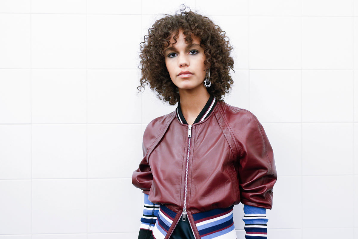 Model with curly hair wearing a cropped leather bomber jacket_Fashion and Style Trends